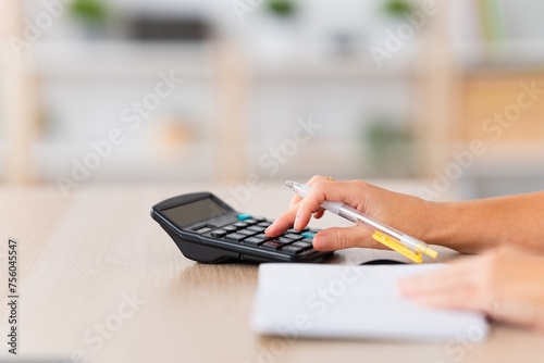 Close-up and focus on the hands of a person using calculator at home
