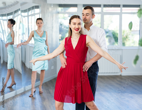 Man and girl take dance lessons from experienced teacher. Couple in stage costumes practices waltz movements, performs coaching instructions. Concept of active hobby, passion for choreography