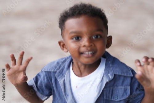 Mixed race African and Asian boy is playing at the outdoor area. smiling happy boy has fun running on the beach. portrait of boy lifestyle with a unique hairstyle.