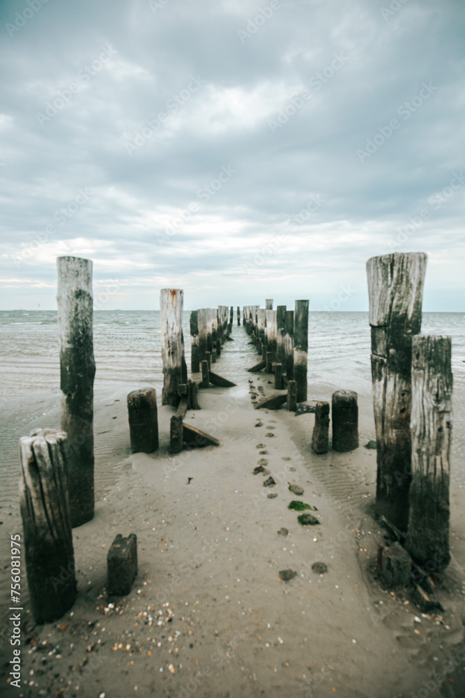 Marine old pier background.Coastline and wooden pier on a cloudy day. Old destroyed wooden pier in the sea on a cloudy day.