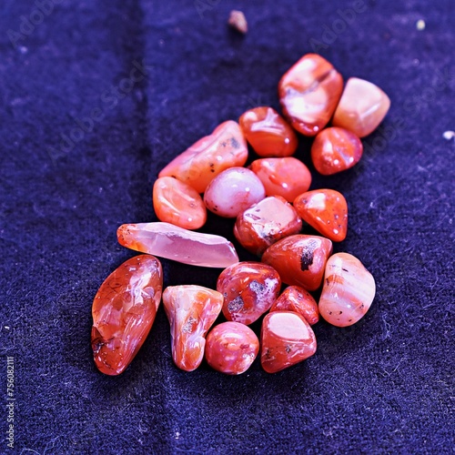 Several red jasper gem stones or healing crystals laying on cotton fabric.  (ID: 756082111)