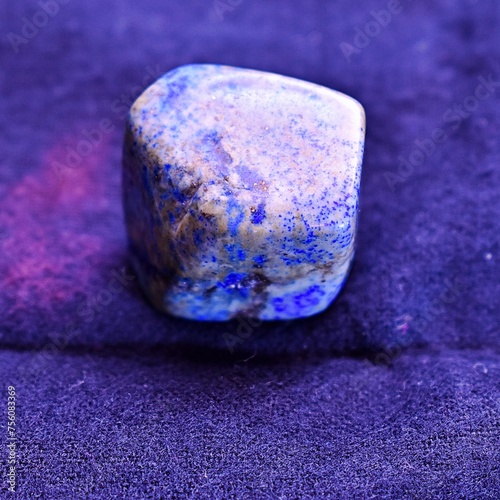 A large lapis lazuli gemstone or healing crystal sitting on top of a piece of cotton fabric.  (ID: 756083369)