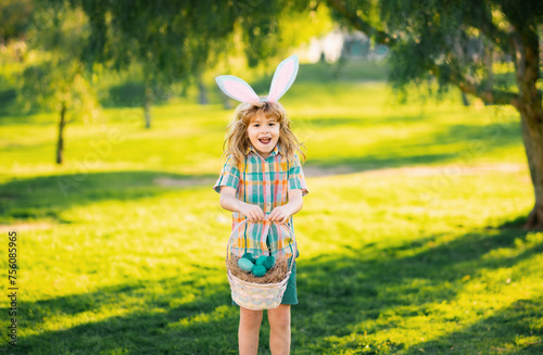 Bunny boy. Kids in bunny ears on Easter egg hunt in garden. Children with colorful eggs in grass. Toddler boy play outdoors. Child hunting easter eggs. © Volodymyr