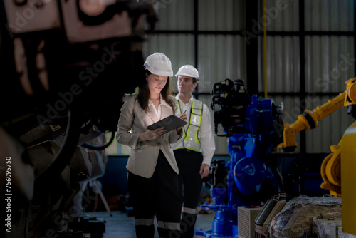 Business woman and man meeting and checking new machine robot. Engineer walking at warehouse industry machine. business negotiation concepts and technology. woman is Using smart Tablet to present man.