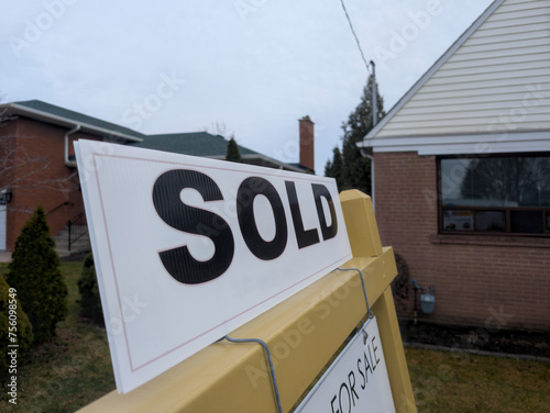 Sign sold in front of detached house in residential area. Real estate bubble, crash, hot housing market, overpriced property, buyer activity, interest rates rise concept. Selective focus.