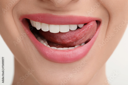 Young woman licking her teeth on white background  closeup