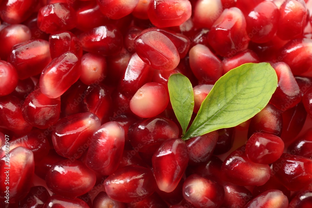 Green leaves on ripe juicy pomegranate grains, top view Green leaves on ripe juicy pomegranate grains, top view