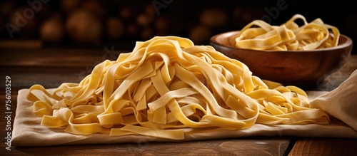 A pile of pasta and a bowl of pasta are displayed on a cutting board. This Italian cuisine staple food is a comforting dish made with simple ingredients