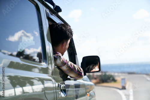 車の窓から体を乗り出して前を見る男性