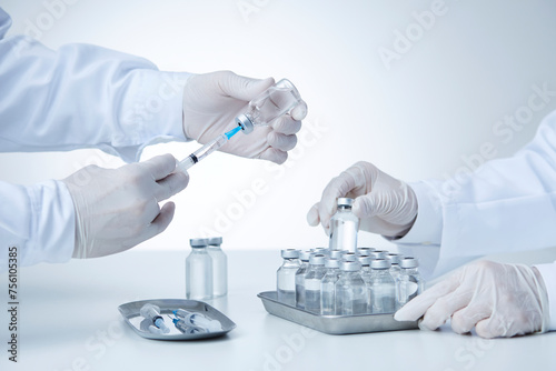 白衣を着てワクチンを触る研究者2人の手元 photo