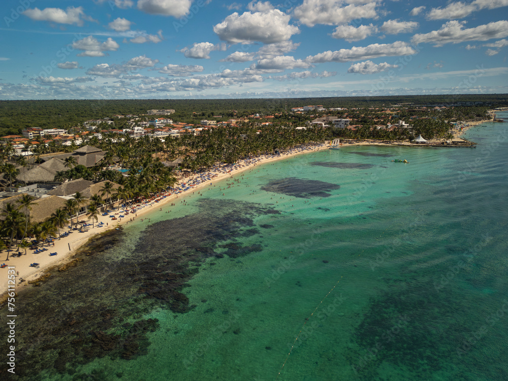 Aerial drone photo of busy white sand beach with many people at all inclusive resort and crystal clear calm turquoise ocean water. South destination, march break holidays, travel concept.