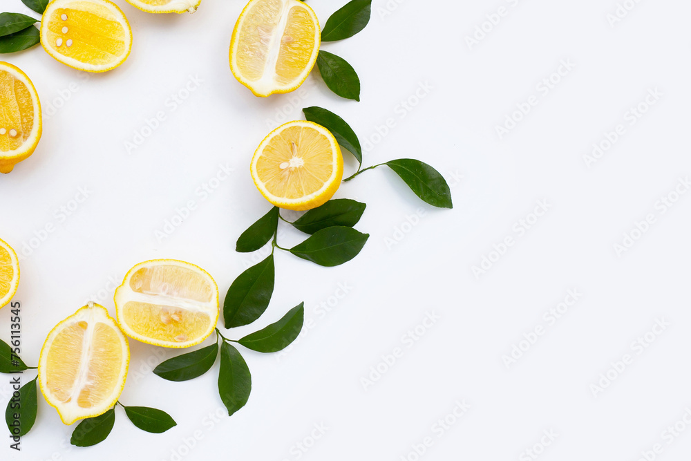 Fresh lemon with green leaves on white.