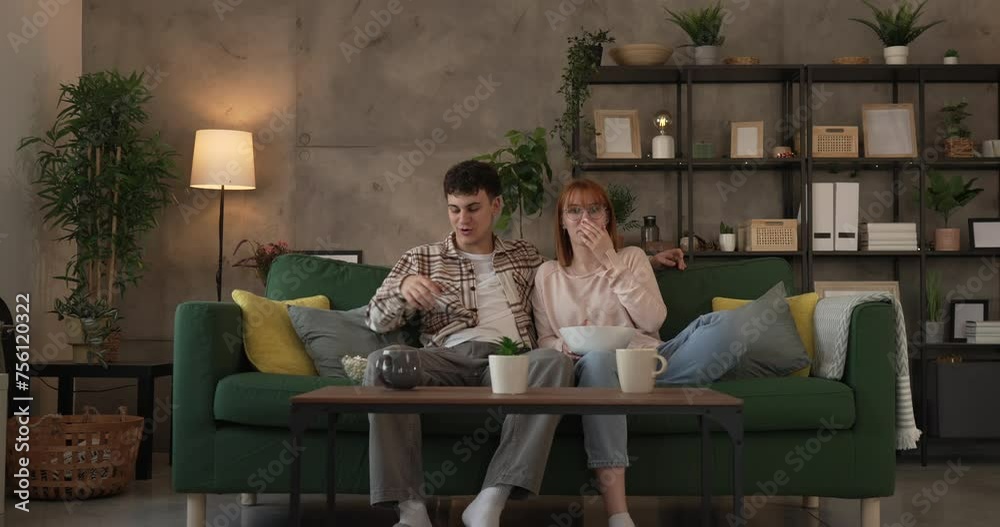 Couple caucasian man and woman sit at home on sofa bed watch tv movie Couple caucasian man and woman sit at home on sofa bed watch tv movie