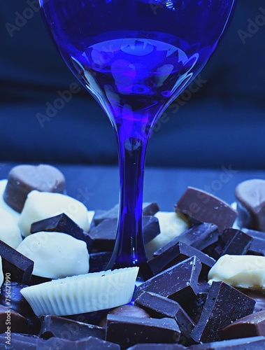 Assorted chocolates surrounding a blue wine glass.  (ID: 756121990)