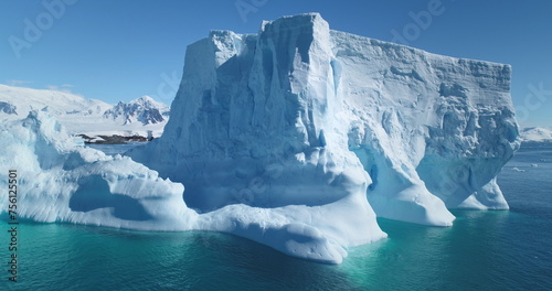 Majestic winter Antarctica iceberg drifting ocean in sunny day. Blue sky, turquoise water. Close up snow covered floating glacier panoramic shot. Ecology, melting ice, climate change, global warming