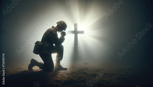 A poignant scene of a soldier in uniform kneeling in solemn prayer beside a rugged cross on a misty battlefield. photo