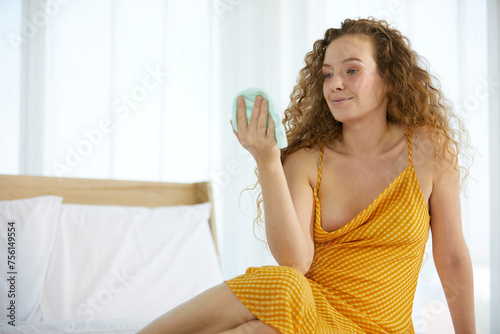 pregnant woman looking cute baby clothes on the bed