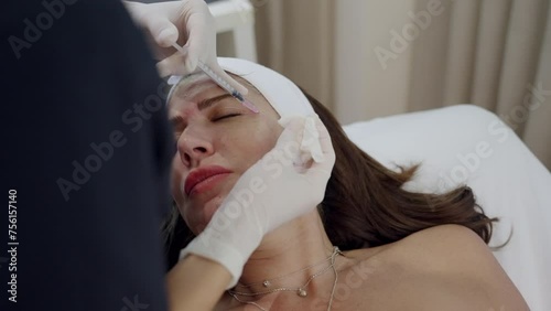 Woman getting face beauty injection in cosmetic clinic. Close up cosmetologist doing botox injection in forehead to patient in beauty clinic. Rejuvenation, injectable cosmetology and medicine concept photo