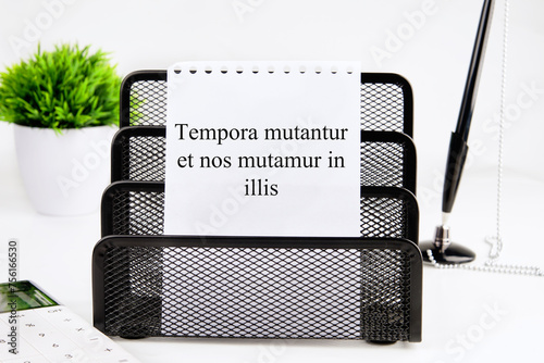 Tempora mutantur et nos mutamur in illis Translated from Latin, it means Times are changing, and we are changing with them. on a white sheet of a notebook in a black stand. Concept photo photo