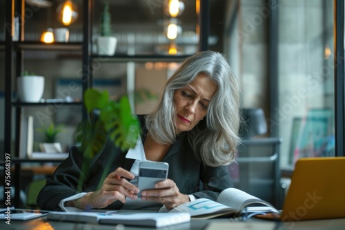 Adult businesswoman inside office at workplace received online notification message with bad news on phone, female boss with gray hair using phone frustrated and displeased reading online,GenerativeAI