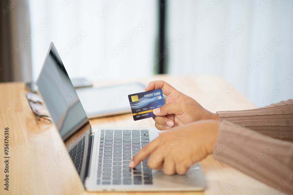 Close Up man hands holding credit card using online shopping with laptop, Online payment at home or office, internet banking, future lifestyle ideas for spending or entrepreneurs in ordering products Close Up man hands holding credit card using online shopping with laptop, Online payment at home or office, internet banking, future lifestyle ideas for spending or entrepreneurs in ordering products