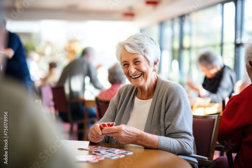 Happy elderly retired woman playing cards with friends in community center