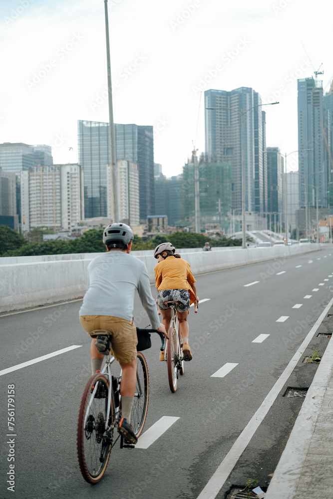A young couple riding their bikes in the city.