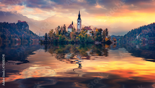 Pilgrimage Church of the Assumption of Maria and foggy mountains reflected in the calm waters of Bled lake. Calm autumn scene of Julian Alps. Great sunrise in Slovenia. Traveling concept background.