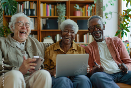 Diverse senior people sitting at home laughing with laptop photo