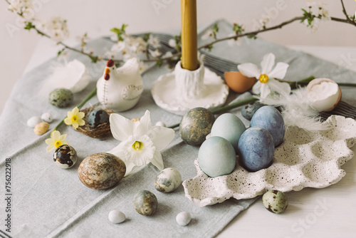 Happy Easter! Stylish easter eggs in tray, cherry blossom and candle on rustic table. Modern natural dyed marble eggs and spring flowers. Easter still life in countryside home