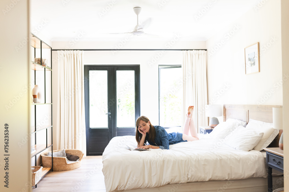 Caucasian woman lounges on a bed, smiling while talking on the phone, with copy space Caucasian woman lounges on a bed, smiling while talking on the phone, with copy space