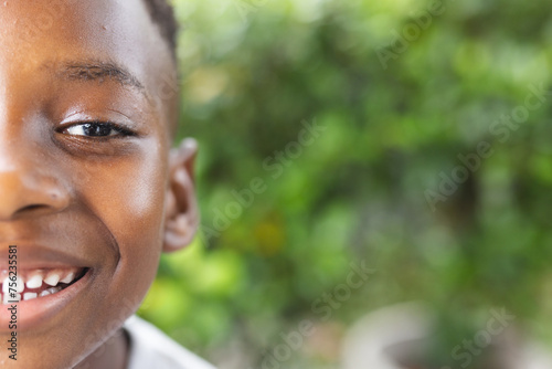 Close-up of a smiling African American boy with a greenery background in a garden with copy space photo