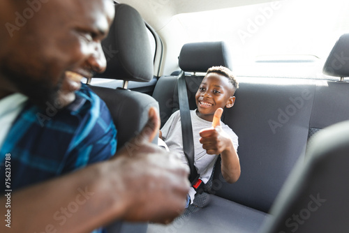 African American father and son share a joyful moment in a car, both giving thumbs up photo