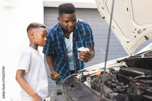 African American father teaches a son about car maintenance photo
