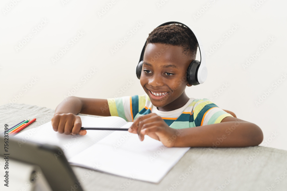 African American boy with headphones studies online at a desk African American boy with headphones studies online at a desk