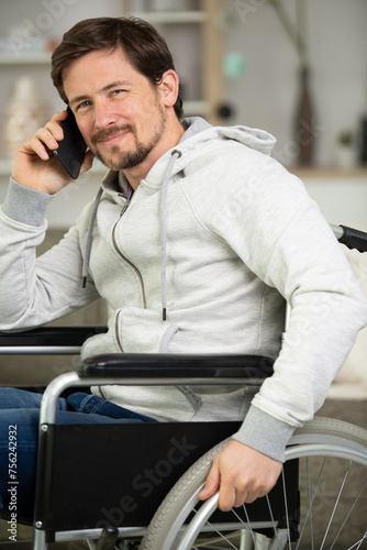 handsome man in wheelchair talking on his phone and smiles