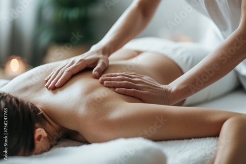 A doctor's hands massaging a young woman's back in a bright room. A cosmetic procedure in a spa salon.