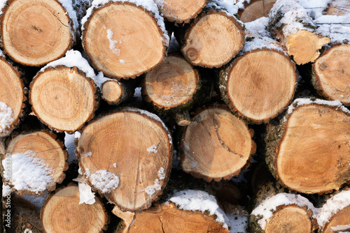 Stacked stacks of firewood. Firewood under the snow. Chopped trunks. background  texture