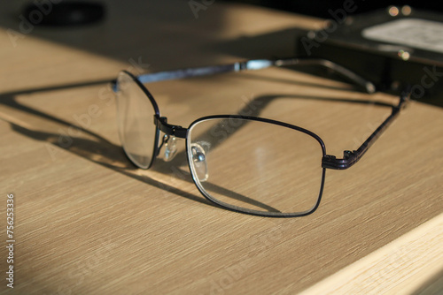 Glasses on a wooden office desk in the light of the evening sun.