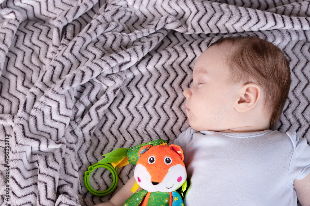 Naklejka premium Adorable child, with a favorite toy, sleeps relaxed and sprawls on the parents' bed