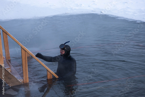 A man in a diving suit. A professional rescue diver is in the hole and ready to help a drowning person.
