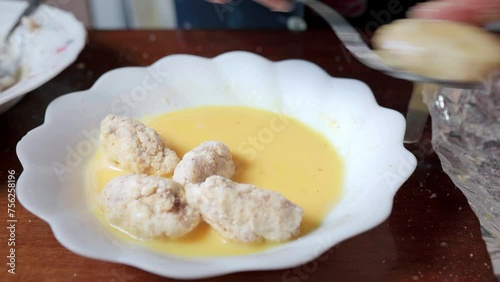Senior woman dipping croquettes in egg to fry them