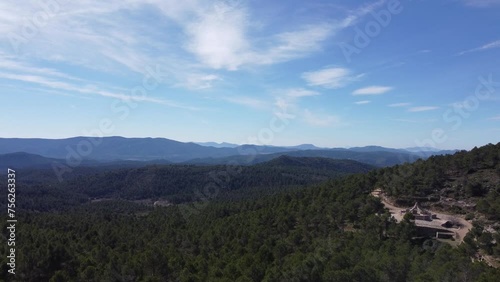 4k dji drone video of a beautiful forest full of trees and vegetation. The drone makes a vertical upward movement where in the foreground we have the forest and in the background mountains and a cabin photo