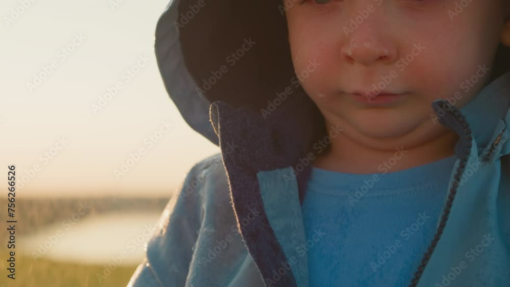 Droplets trace down despondent boy face closeup. Forsaken little boy head bowed sheds tears alone with harsh weather mirroring inner turmoil