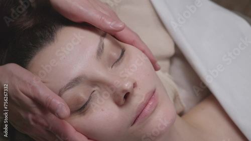 young woman relaxes during a face massage at spa close-up. Slow motion