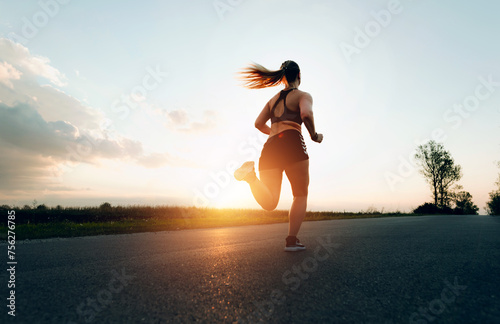 Young Sporty woman running at sunset on the road.Concept of health  slimming and maintaining youth.