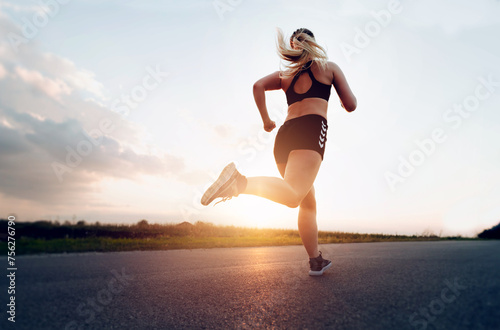 Young Sporty woman running at sunset on the road.Concept of health, slimming and maintaining youth.