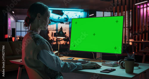 Over the Shoulder: Female Caucasian Specialist Working on Computer with Chroma Key Display at Creative Agency. Young Woman Sitting at Her Desk Using Desktop Computer with Mock-up Green Screen