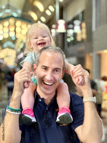 Enfant fille de 1 an et demi sur les   paules de son papa tous deux souriant