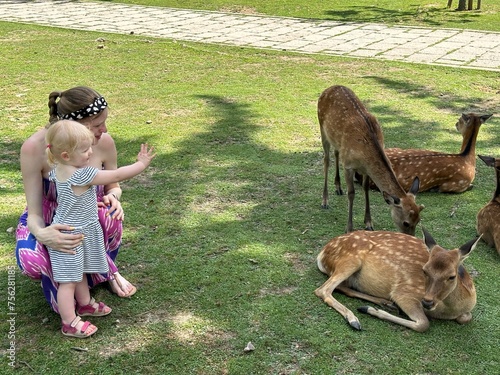 Enfant fille de 1 an et demi saluant des faons avec sa maman au Japon